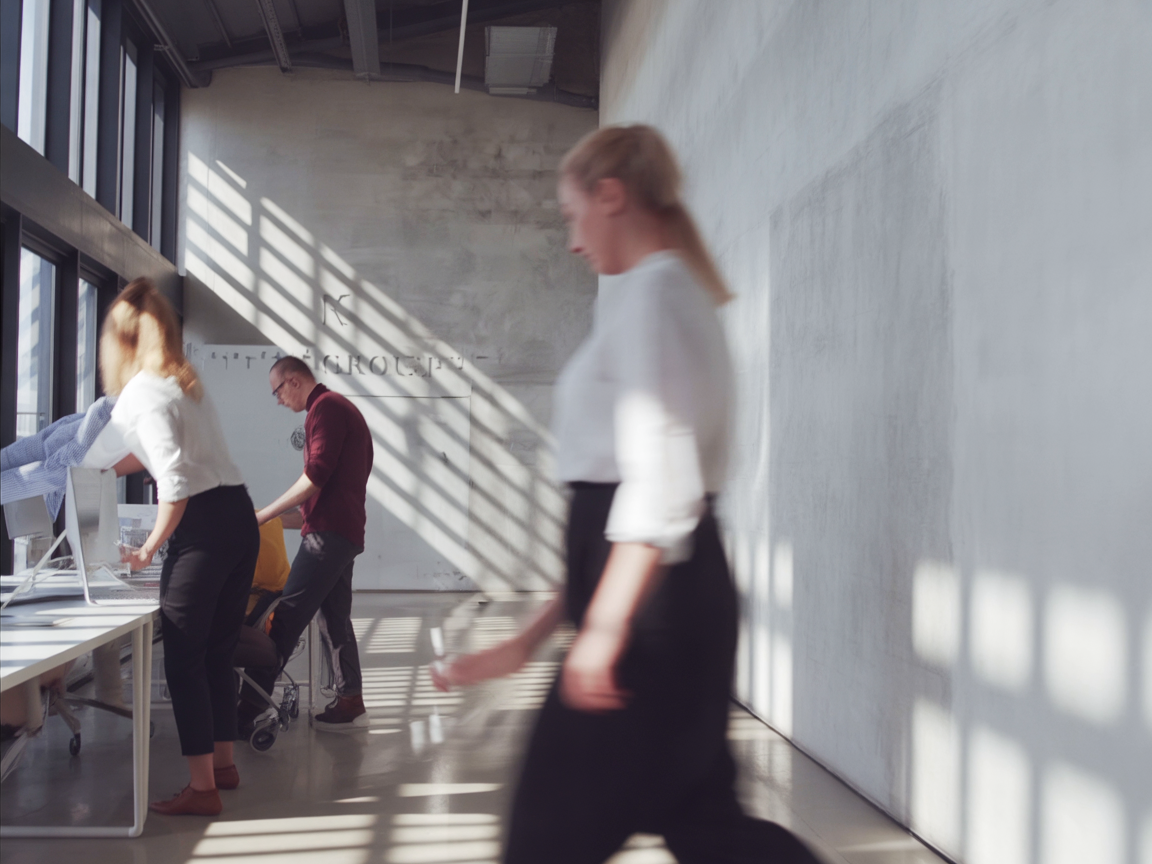 Persone in un ufficio moderno con ampie finestre che lasciano entrare la luce solare.